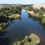aerial view of river with green border of trees
